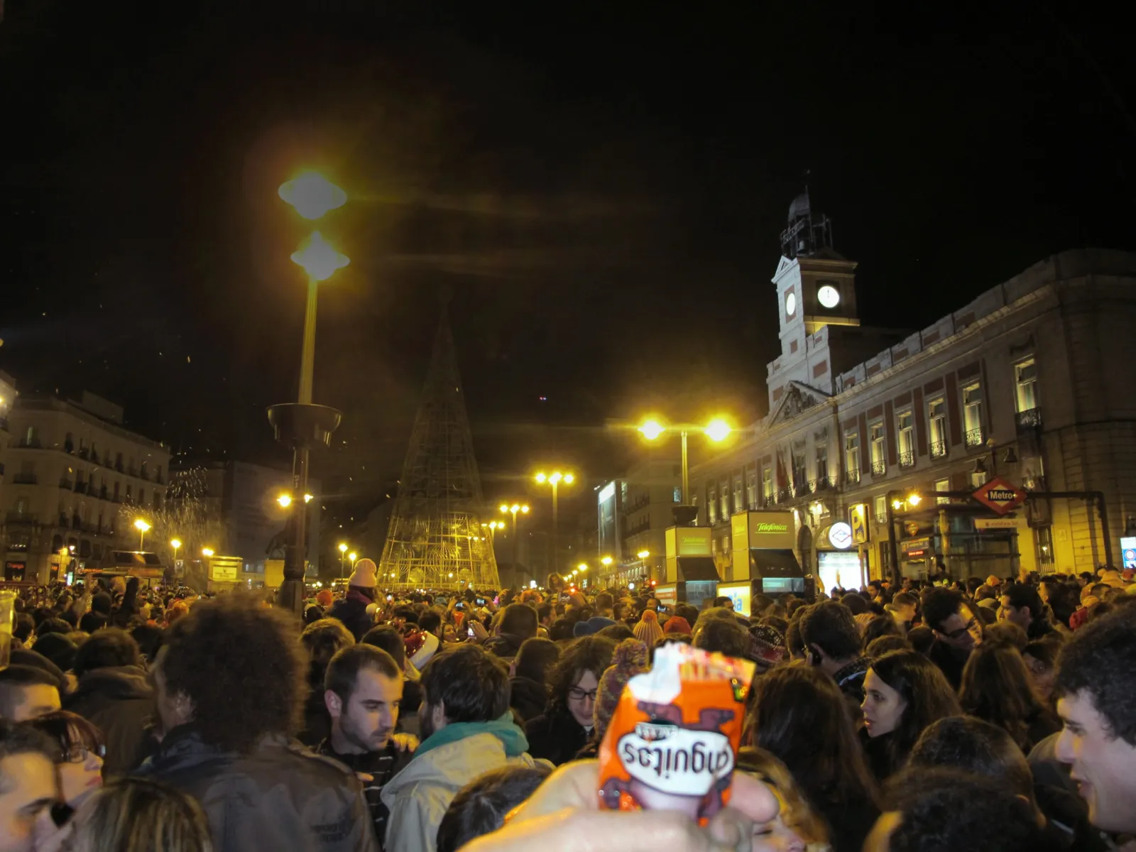 Crowd packing Puerta del Sol at midnight for the Preuvas rehearsal on 30 December, beneath the clock tower of the Real Casa de Correos